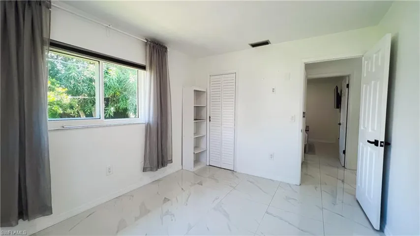 Unfurnished bedroom featuring light marble finish flooring and a closet