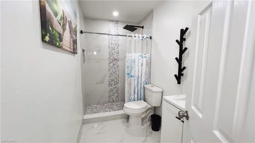 Bathroom with vanity, a stall shower, and light marble finish floors