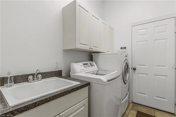 Laundry area featuring cabinets, washing machine and dryer, sink, and light tile patterned floors