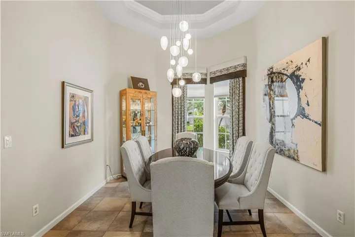 Dining area featuring a notable chandelier, tile patterned floors, a high ceiling, and a tray ceiling
