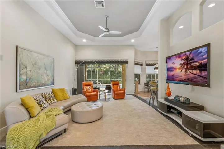 Living room with patterned flooring, a towering ceiling, a raised ceiling, and ceiling fan