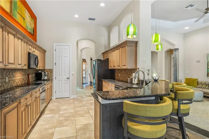 Kitchen featuring tasteful tile backsplash, ceiling fan, stainless steel appliances, light tile , and decorative light fixtures