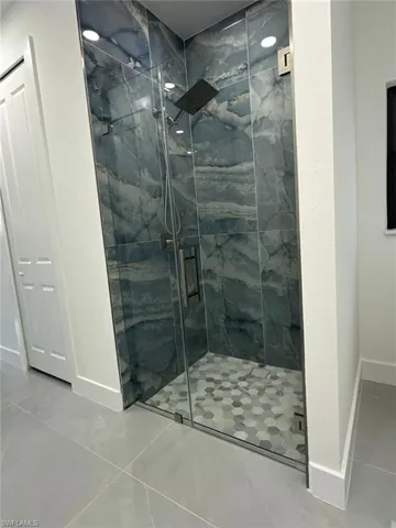 Bathroom with a marble finish shower and tile patterned flooring