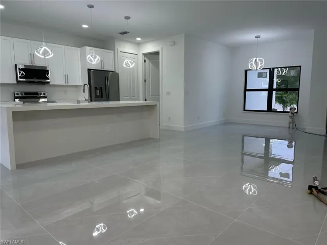 Kitchen with appliances with stainless steel finishes, light countertops, white cabinets, decorative light fixtures, and recessed lighting