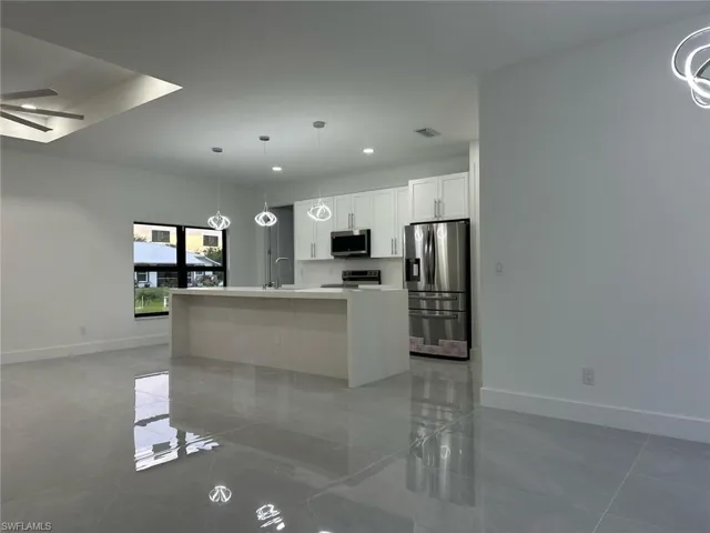 Kitchen featuring stainless steel appliances, a ceiling fan, light countertops, white cabinets, and recessed lighting