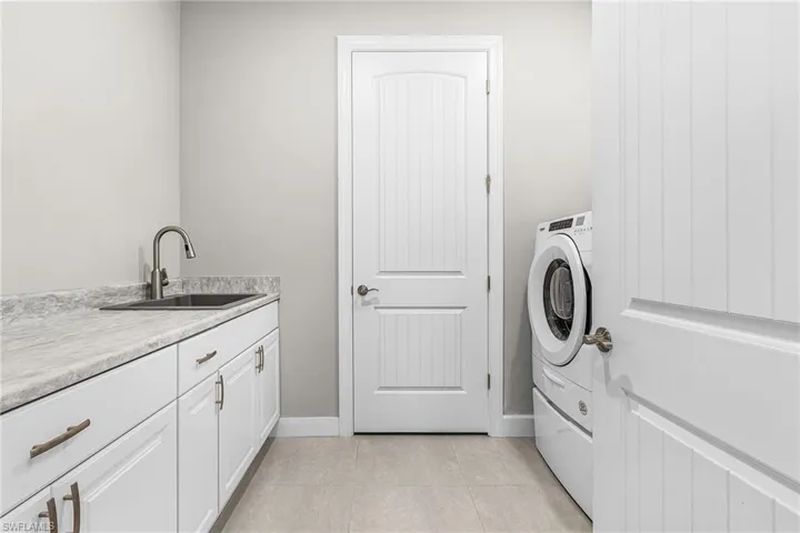 Laundry room with light tile patterned floors, cabinet space, and washer / clothes dryer