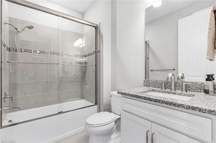 Bathroom featuring enclosed tub / shower combo, vanity, and light tile patterned floors