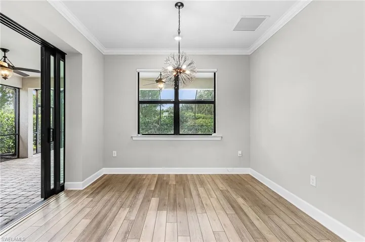Unfurnished room featuring a tray ceiling, light wood finished floors, crown molding, and ceiling fan