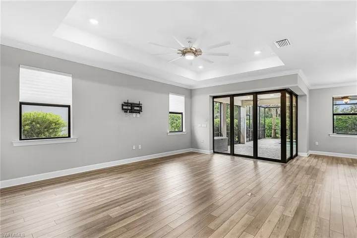 Spare room with a ceiling fan, a tray ceiling, ornamental molding, light wood-style floors, and recessed lighting