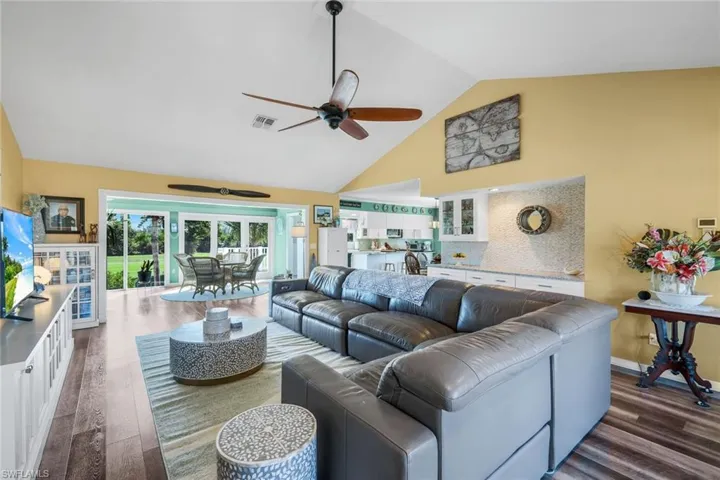 Living area featuring high vaulted ceiling, ceiling fan, and dark wood-style floors