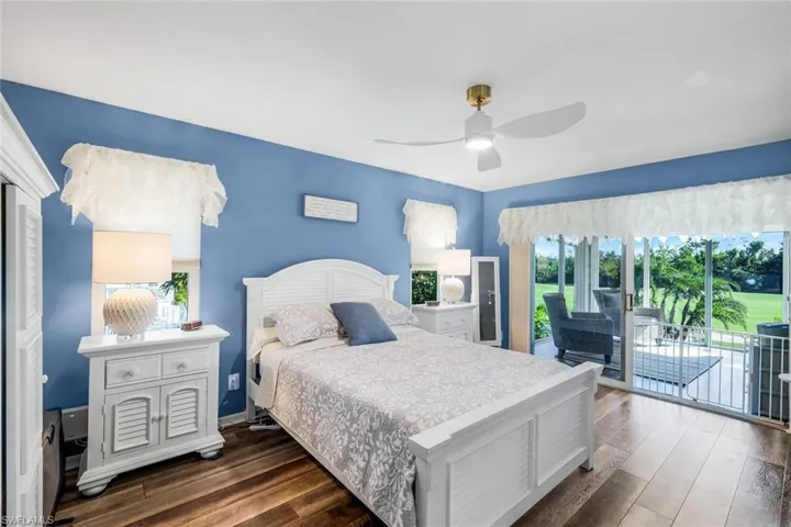 Bedroom featuring access to outside, dark wood-style floors, and a ceiling fan