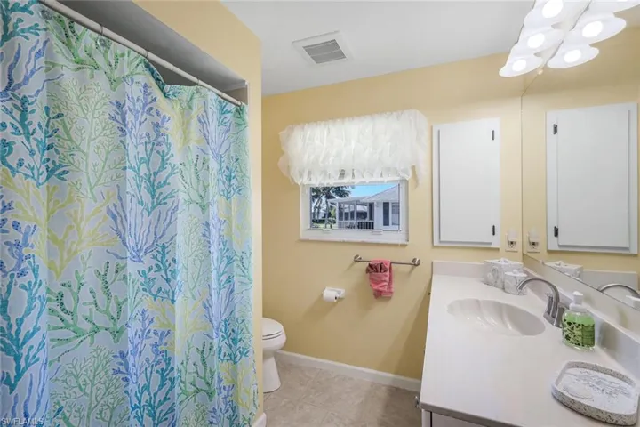 Full bath featuring vanity, a shower with shower curtain, light tile patterned floors, and a chandelier