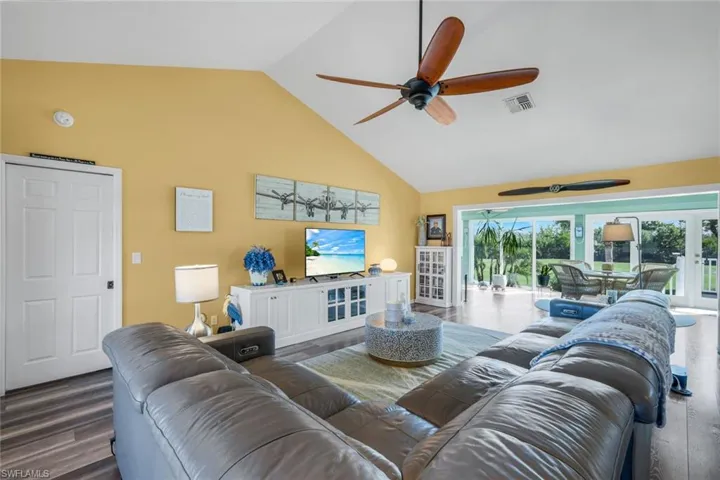 Living room featuring high vaulted ceiling, dark wood-type flooring, and ceiling fan
