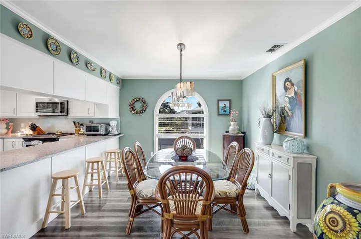 Dining area featuring a chandelier, crown molding, and dark wood-style flooring