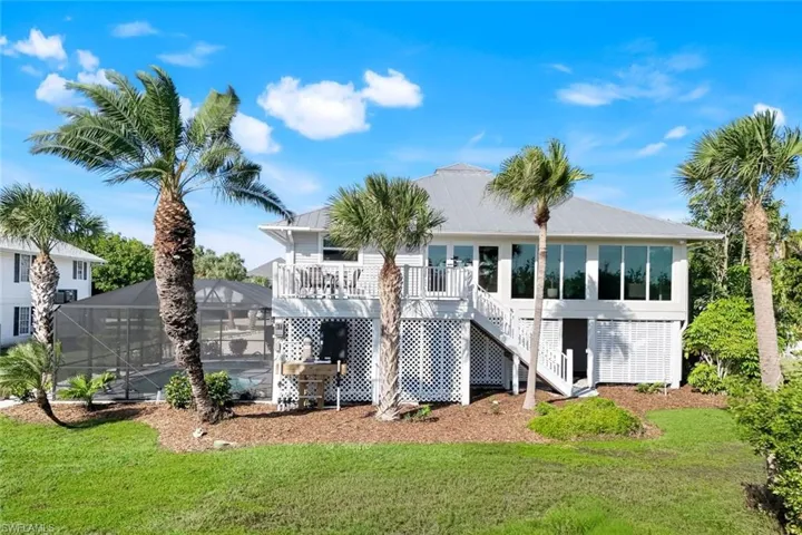 Back of house featuring a sunroom, a deck, stairway, glass enclosure, and a lawn