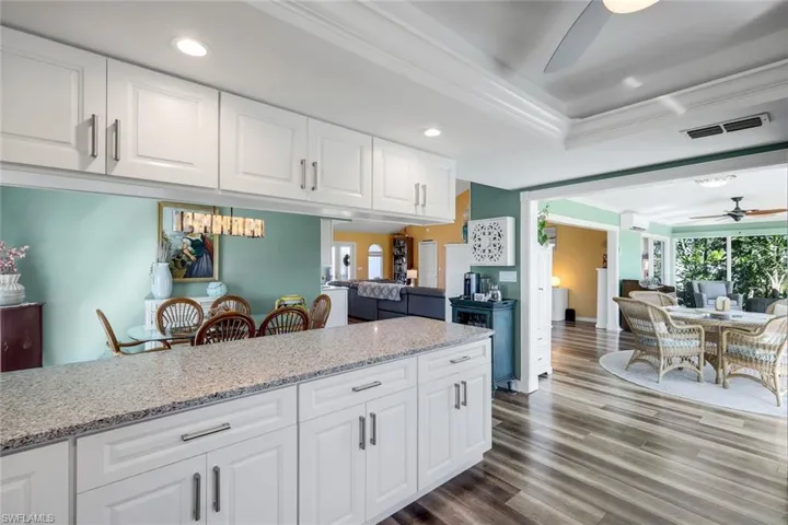 Kitchen with a ceiling fan, light stone counters, white cabinetry, open floor plan, and recessed lighting