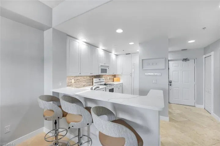 Breakfast bar and partial view of kitchen and entryway.