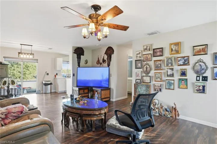 Living room featuring a ceiling fan and dark wood-style floors