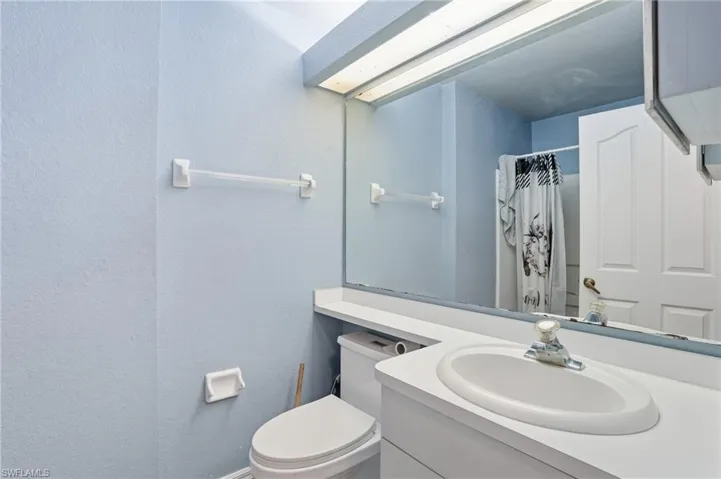 Full bathroom featuring vanity, a shower with shower curtain, and a textured wall