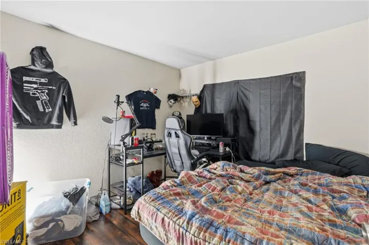 Bedroom featuring dark wood-style floors and a textured wall