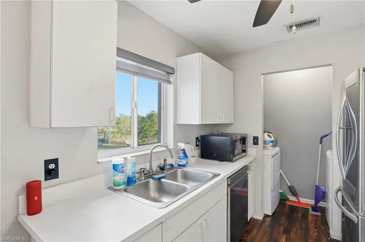 Kitchen featuring light countertops, stainless steel appliances, white cabinetry, dark wood finished floors, and a ceiling fan