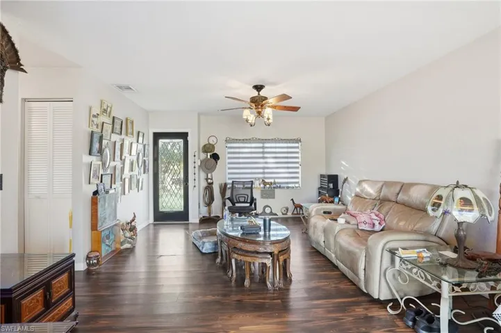 Living room with dark wood finished floors and a ceiling fan