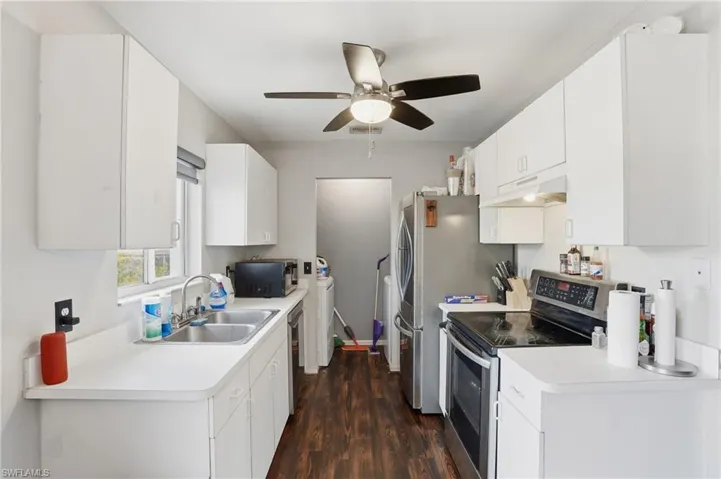 Kitchen with stainless steel appliances, light countertops, dark wood finished floors, and under cabinet range hood