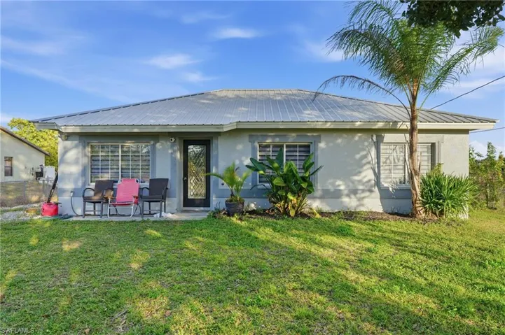 Rear view of house with stucco siding, a metal roof, and a patio