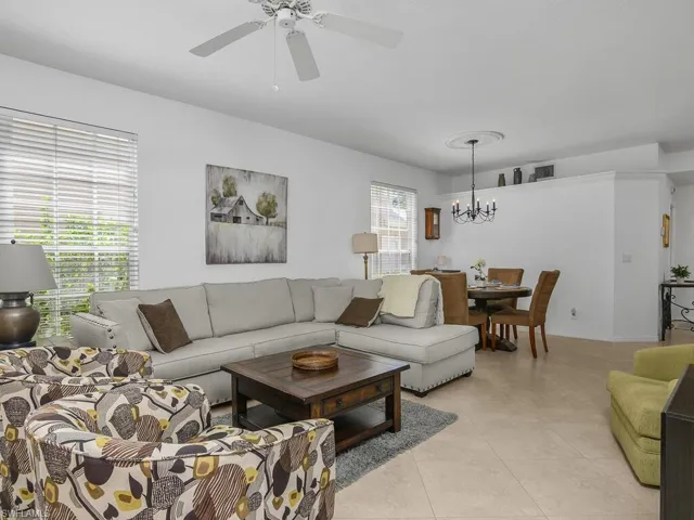 Living area featuring a ceiling fan, hanging lights, and light tile floors