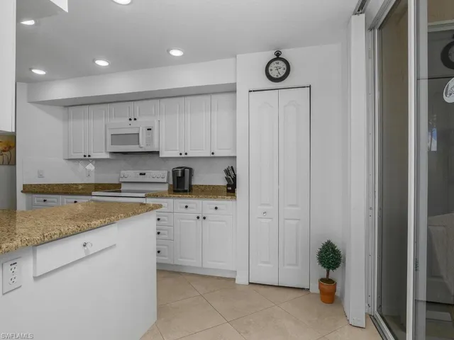 Kitchen featuring  granite countertops, white cabinets, white appliances, tasteful backsplash, and recessed lighting