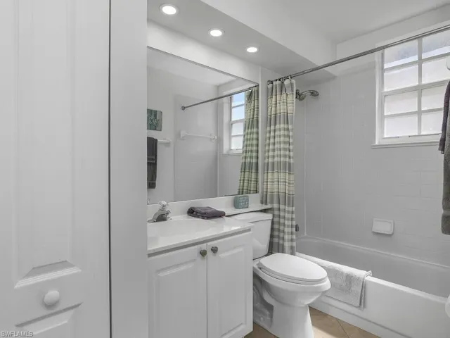 Full bathroom with vanity, shower / bath combo, light tile flooring, and recessed lighting