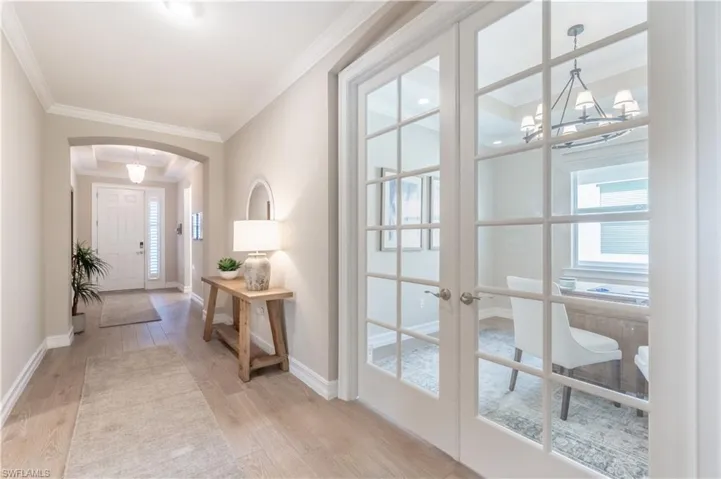Entrance foyer featuring french doors, ornamental molding, light hardwood / wood-style flooring, and a chandelier