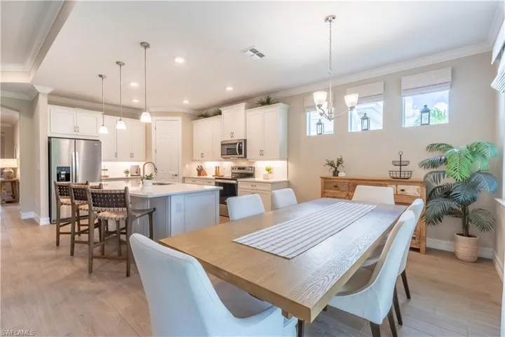 Dining room with light hardwood / wood-style floors, crown molding, sink, and an inviting chandelier