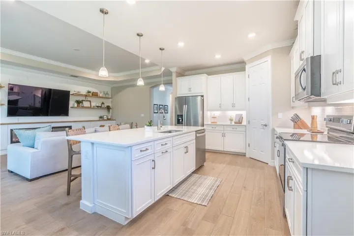 Kitchen featuring white cabinets, an island with sink, sink, pendant lighting, and stainless steel appliances