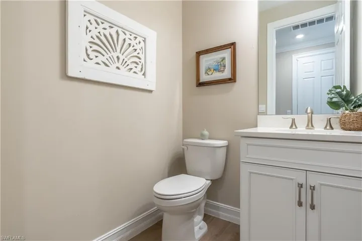 Bathroom featuring vanity, crown molding, hardwood / wood-style flooring, and toilet