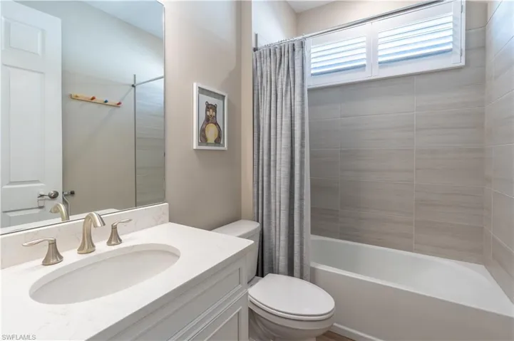 Full bathroom with toilet, shower / tub combo with curtain, and vanity
