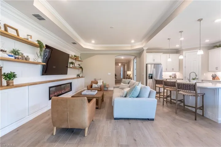 Living room featuring light hardwood / wood-style flooring, ornamental molding, and a tray ceiling