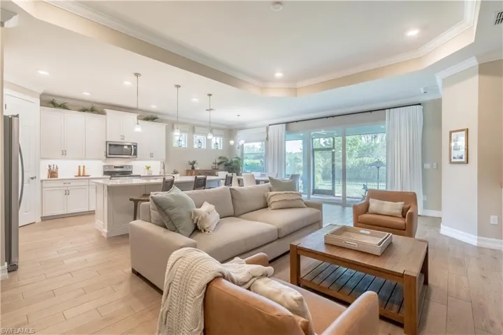 Living room with ornamental molding, light hardwood / wood-style flooring, and a tray ceiling