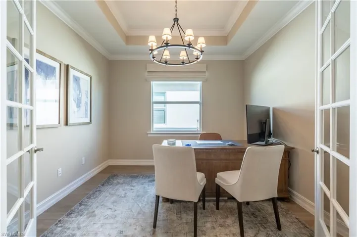 Home office with an inviting chandelier, a tray ceiling, wood-type flooring, and crown molding