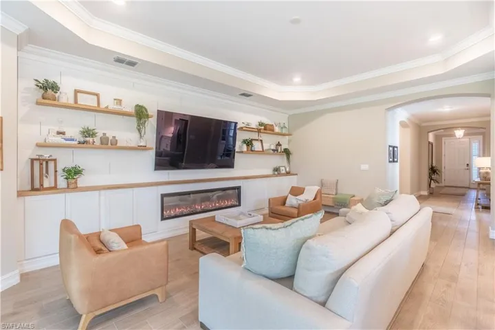 Living room with light hardwood / wood-style floors, a raised ceiling, and ornamental molding