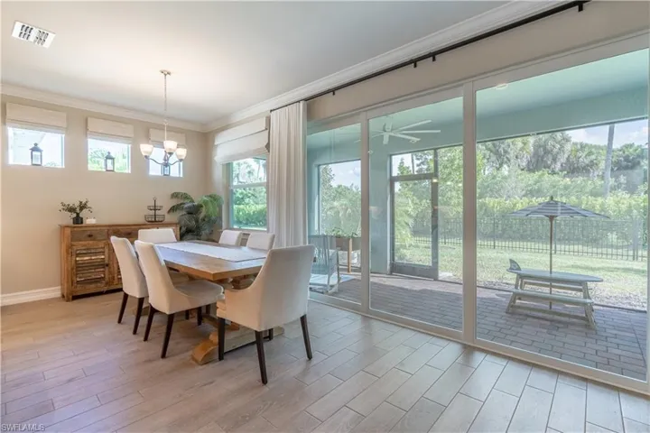 Dining space with crown molding, ceiling fan with notable chandelier, light wood-type flooring, and a healthy amount of sunlight