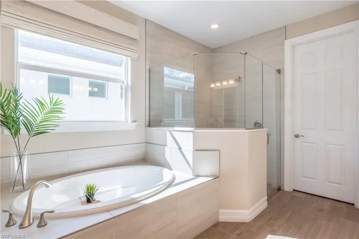 Bathroom featuring wood-type flooring and plus walk in shower