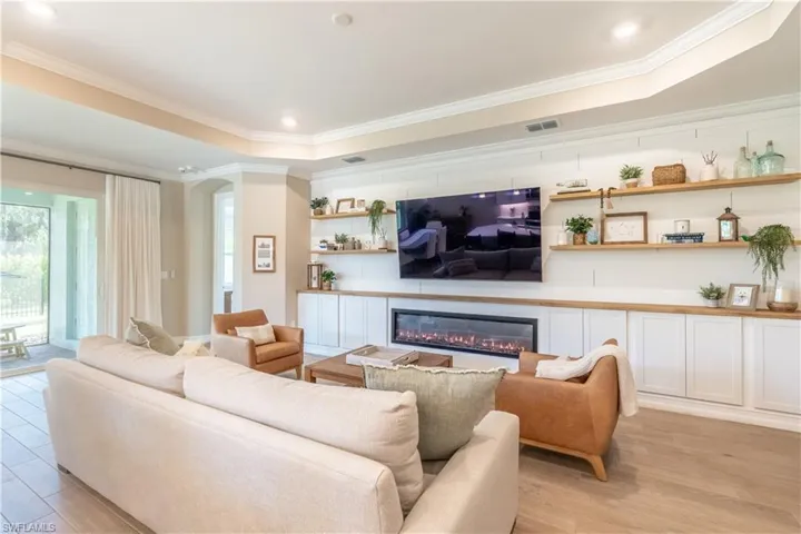 Living room with light hardwood / wood-style flooring, crown molding, and a raised ceiling
