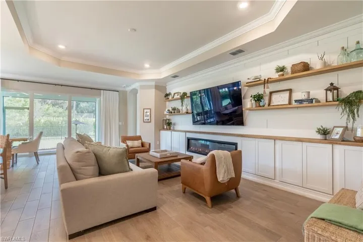 Living room featuring light hardwood / wood-style flooring, ornamental molding, and a tray ceiling