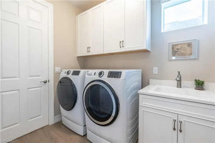 Laundry area featuring cabinets, independent washer and dryer, sink, and light wood-type flooring