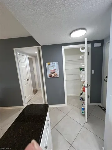 Hall with a textured ceiling and light tile patterned floors
