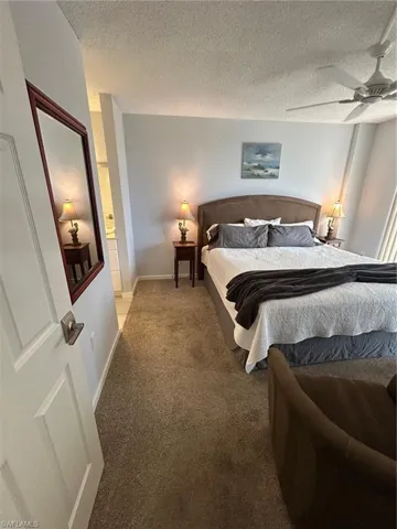 Carpeted bedroom with a textured ceiling and a ceiling fan