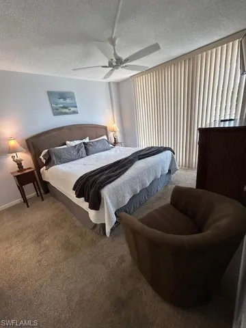 Carpeted bedroom featuring a textured ceiling and a ceiling fan