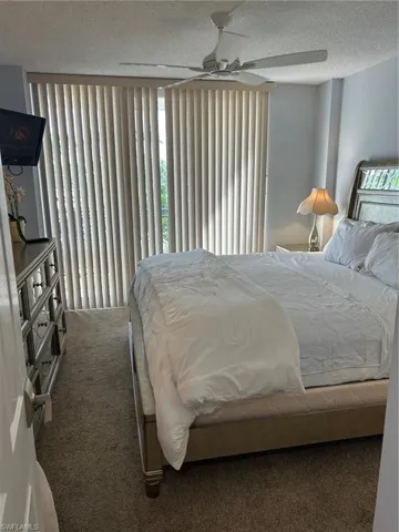 Carpeted bedroom with a textured ceiling and a ceiling fan