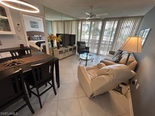 Living room with floor to ceiling windows, light tile patterned floors, a ceiling fan, and a textured ceiling